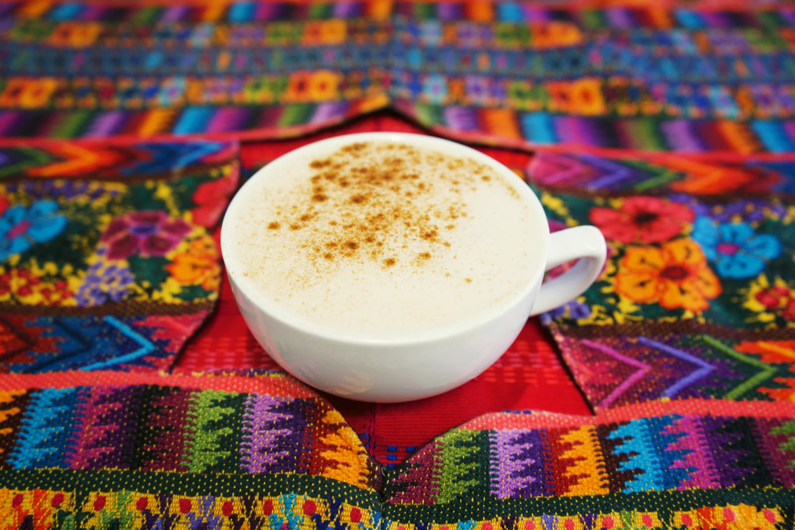 Cappuccino with cinnamon on a colorful woven tablecloth